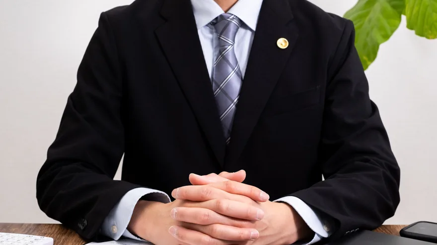机に手を組む弁護士